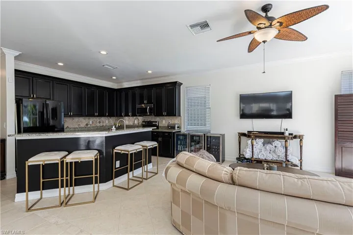 Tiled living room featuring ceiling fan, crown molding, and sink