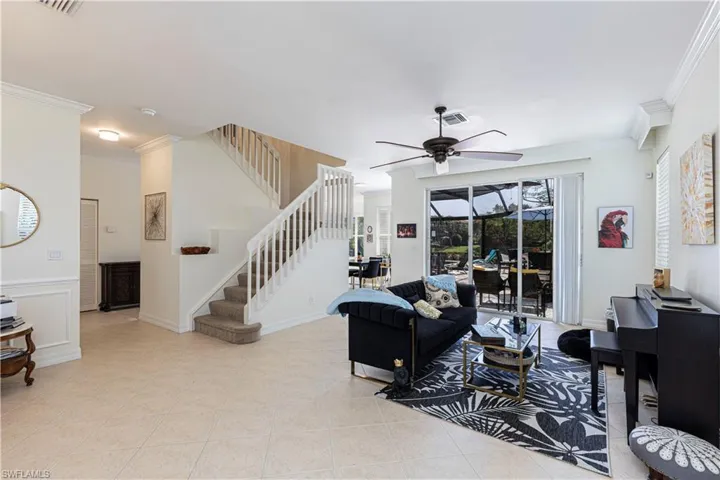 Living room featuring ceiling fan, ornamental molding, and light tile floors