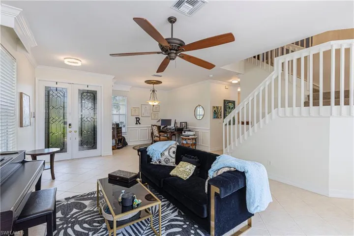Tiled living room featuring ornamental molding, ceiling fan, and french doors