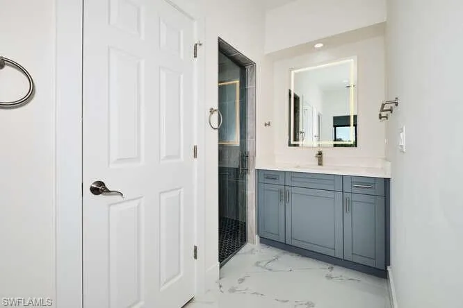 Bathroom featuring a shower stall, vanity, and light marble finish floors