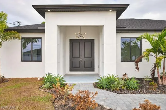 Entrance to property featuring stucco siding and roof with shingles