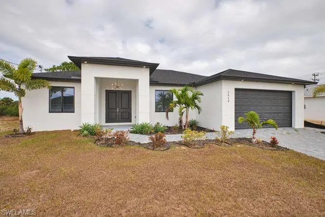 View of front of property featuring stucco siding, a garage, decorative driveway, and a front yard