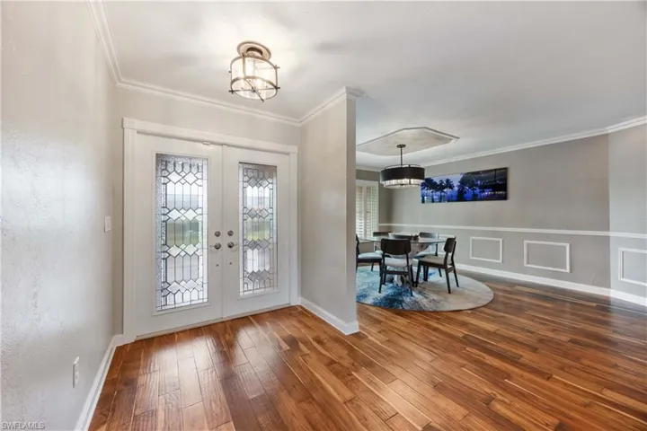 Foyer featuring French door entrance, beautiful wood flooring, detail wall moldings, and a new dining light fixture