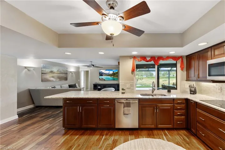 Updated Kitchen featuring cooktop, wood floors, dishwasher, custom cabinets, under cabinet lighting and decorative backsplash