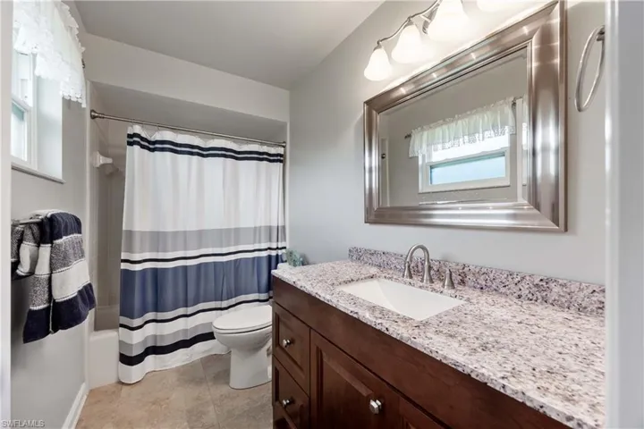 Full bathroom with tile flooring, vanity, shower-tub combo