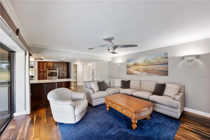 Family room with new ceiling fan, wood floors, and crown molding detailing opens to kitchen area