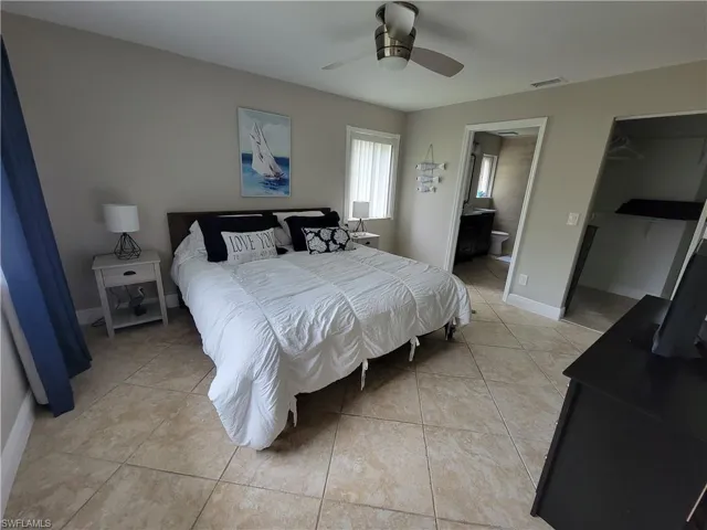 Bedroom featuring connected bathroom, ceiling fan, and light tile floors
