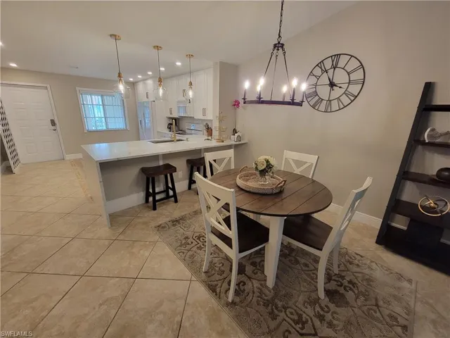 Dining area with a notable chandelier, sink, and light tile floors
