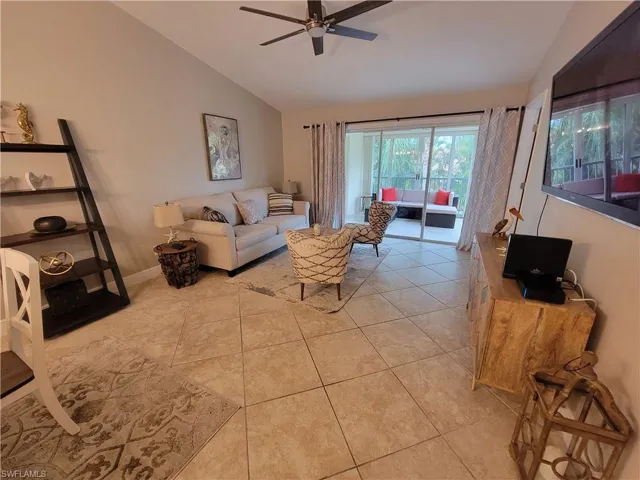 Living room featuring ceiling fan, light tile floors, and lofted ceiling