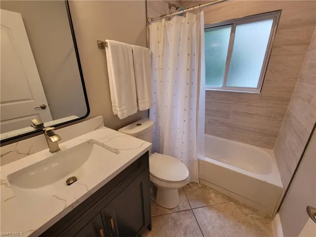 Full bathroom featuring toilet, vanity, shower / bath combo, and tile floors