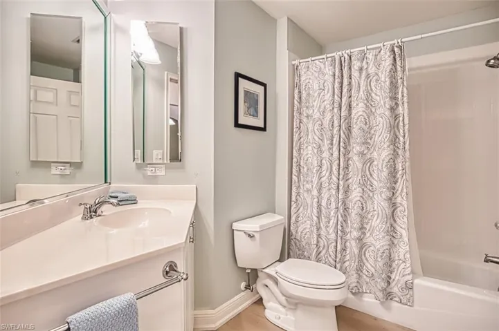 Bathroom featuring shower / bath combination with curtain, vanity, and light wood-style flooring