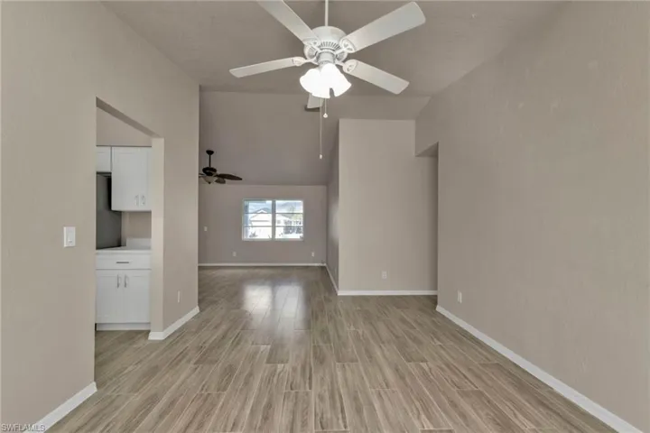 Unfurnished living room with light hardwood / wood-style floors, vaulted ceiling, and ceiling fan