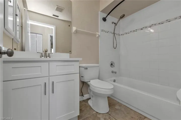 Full bathroom featuring tile patterned floors, vanity, tiled shower / bath combo, and toilet