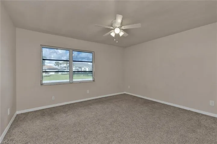 Carpeted spare room featuring ceiling fan