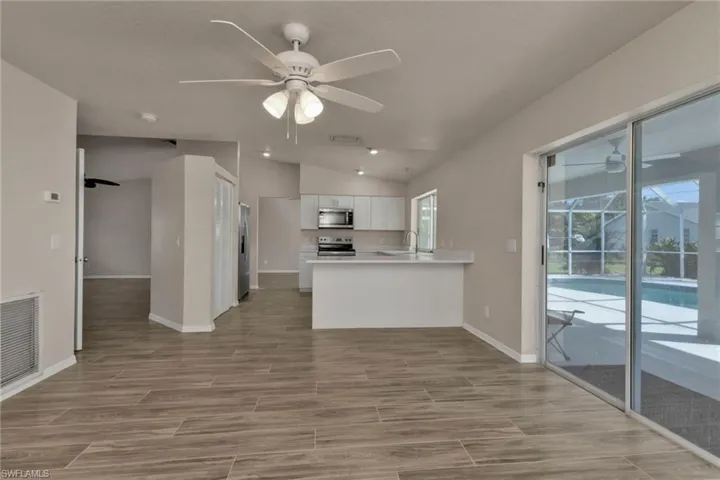 Kitchen featuring ceiling fan, kitchen peninsula, lofted ceiling, white cabinets, and appliances with stainless steel finishes