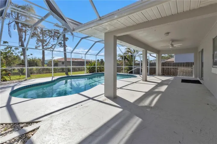 View of pool with a patio, glass enclosure, and ceiling fan