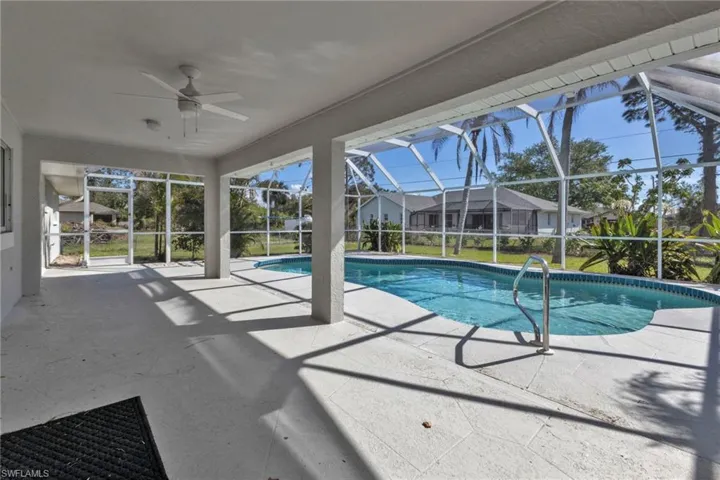 View of pool featuring ceiling fan, a patio, and glass enclosure