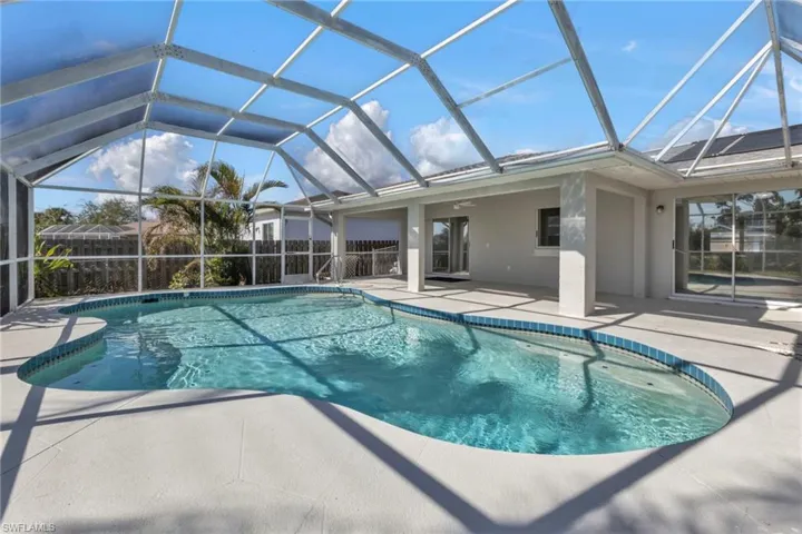 View of swimming pool featuring glass enclosure, ceiling fan, and a patio