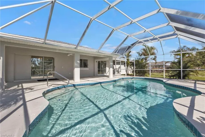 View of swimming pool featuring glass enclosure, ceiling fan, and a patio