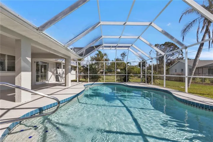 View of pool with glass enclosure and a patio