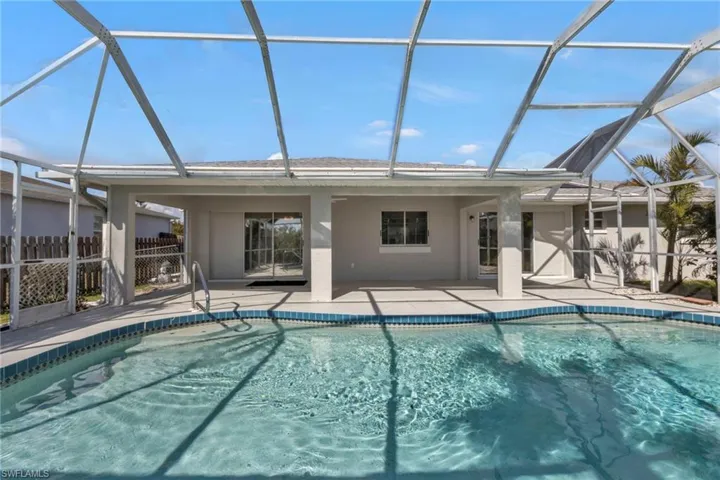View of swimming pool with glass enclosure and a patio