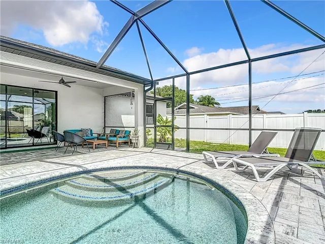 View of swimming pool with glass enclosure, an outdoor living space, a patio area, and ceiling fan