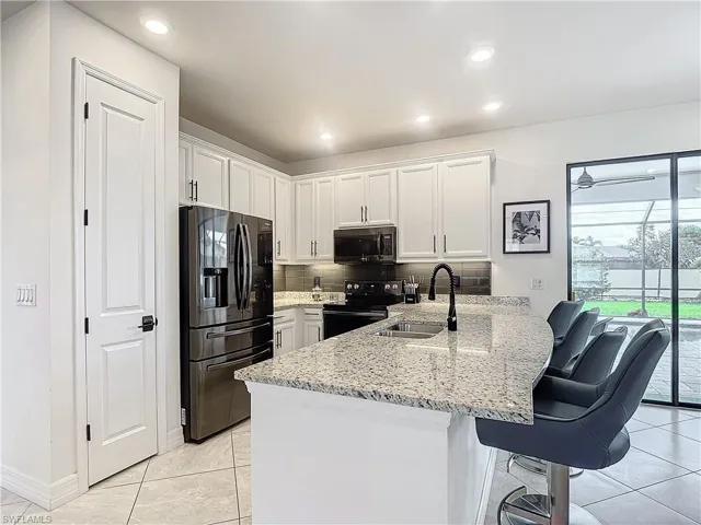 Kitchen with appliances with stainless steel finishes, sink, tasteful backsplash, and white cabinetry