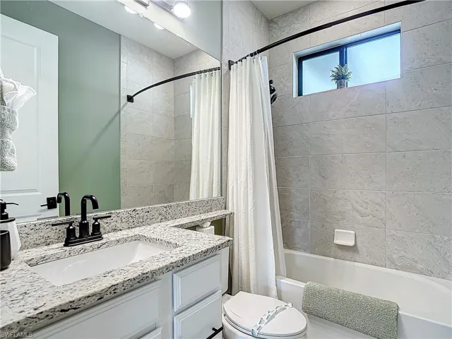 Full bathroom featuring vanity, toilet, and shower / bath combination with curtain