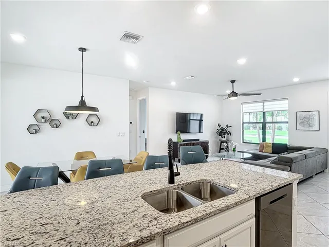 Kitchen with sink, decorative light fixtures, light stone countertops, ceiling fan, and stainless steel dishwasher