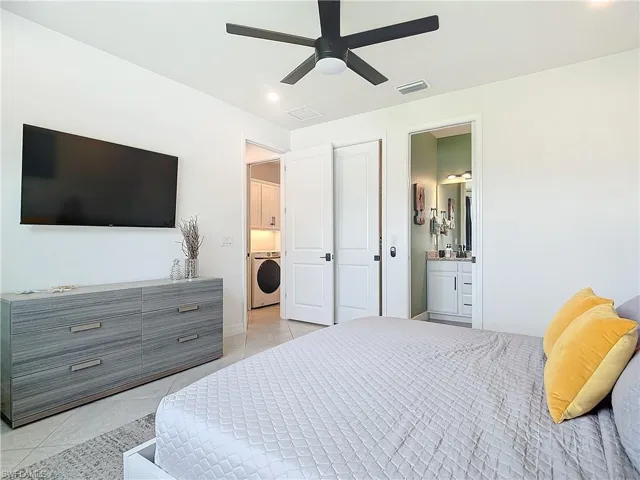 Tiled bedroom with washer / clothes dryer, ceiling fan, and ensuite bathroom