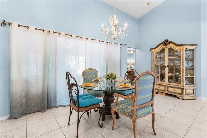 Dining room featuring hanging lights, light tile patterned floors, and vaulted ceiling
