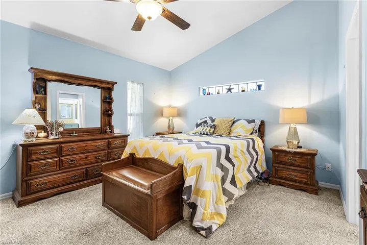 Bedroom with vaulted ceiling, light colored carpet, and ceiling fan