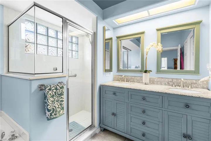 Full bath with double vanity, a shower stall, and a garden tub