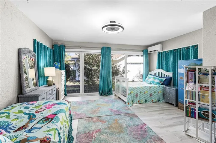 Bedroom with a textured wall, light wood-type flooring, and multiple windows