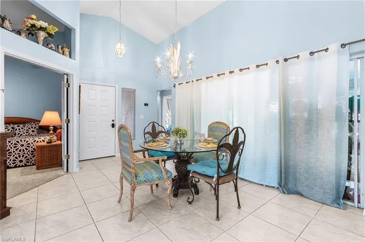 Dining room featuring vaulted ceiling, suspended lighting, and light tile patterned floors