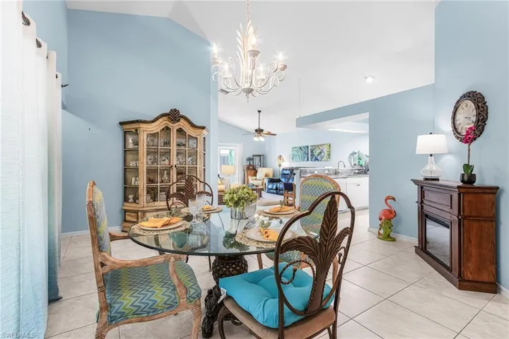 Dining room featuring vaulted ceiling, hanging lights, a ceiling fan, and light tile patterned floors