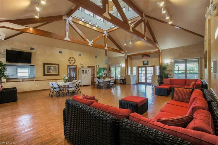 Living area featuring rail lighting, wood-type flooring, a high ceiling, and healthy amount of natural light