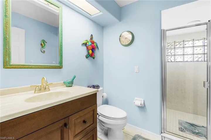 Bathroom with vanity, a stall shower, a skylight, and light tile patterned floors