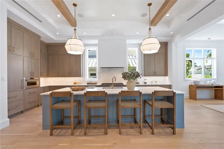 Kitchen featuring a kitchen island with sink, a breakfast bar area, hanging light fixtures, light wood-type flooring, and backsplash
