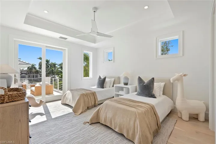 Bedroom with access to exterior, light wood-style flooring, recessed lighting, and a raised ceiling