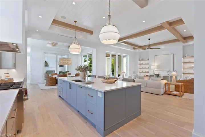 Kitchen with open floor plan, recessed lighting, light wood finished floors, a center island with sink, and light stone countertops
