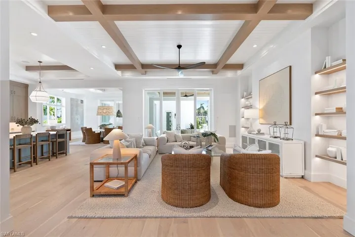 Living area featuring plenty of natural light, light wood-style flooring, beamed ceiling, and a ceiling fan