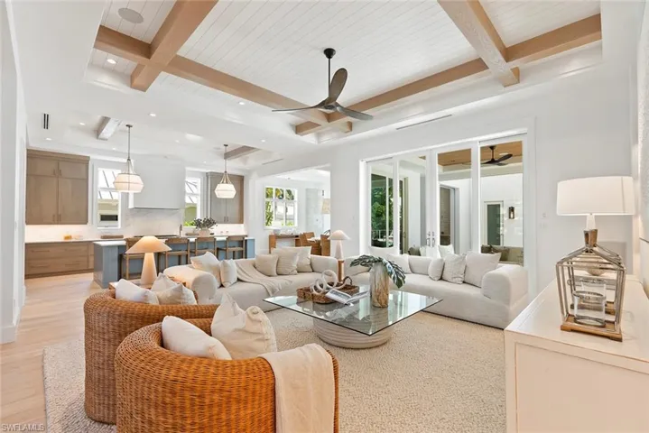 Living room with beam ceiling, a ceiling fan, and light wood-style floors