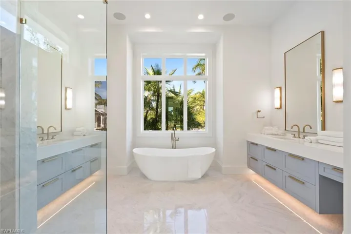 Full bathroom with two vanities, a freestanding tub, and recessed lighting