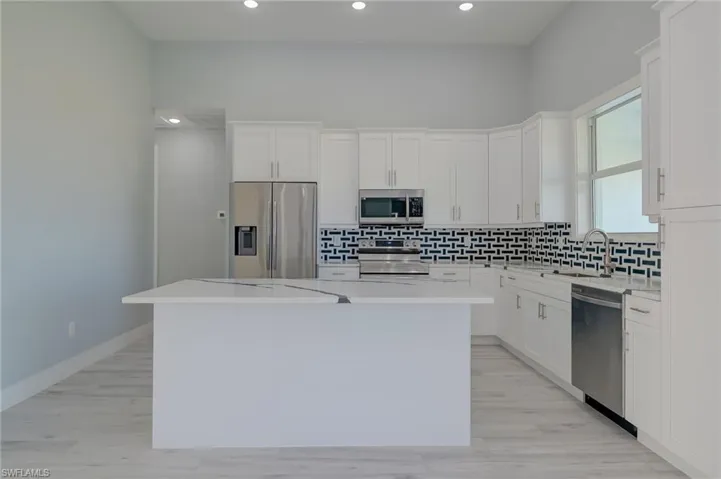 Kitchen featuring stainless steel appliances, white cabinetry, and a center island