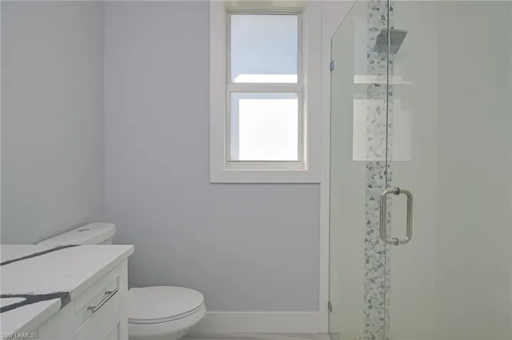 Bathroom featuring vanity, toilet, and an enclosed shower