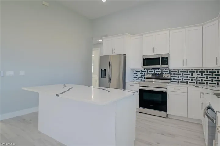 Kitchen featuring a center island, appliances with stainless steel finishes, and white cabinetry