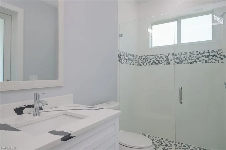 Bathroom with walk in shower, vanity, and toilet