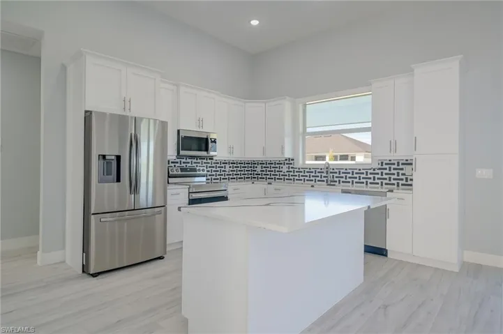 Kitchen featuring sink, white cabinets, a kitchen island, light hardwood / wood-style flooring, and appliances with stainless steel finishes