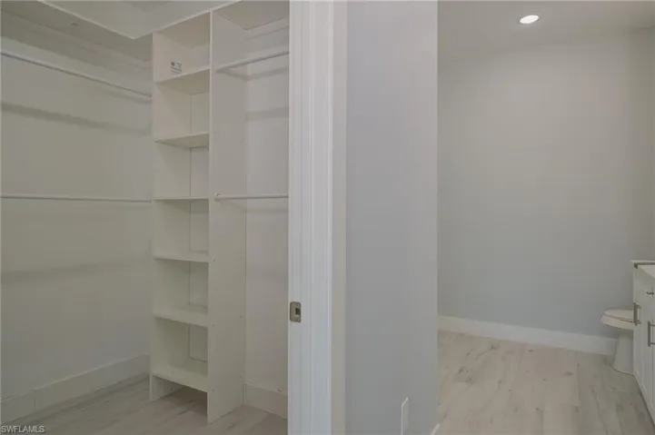 Spacious closet with light hardwood / wood-style flooring